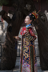 古服穿清宫服的青年女人站在古树下背景