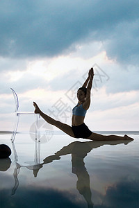 两腿分高举手臂年轻女人在水面上练习瑜伽背景