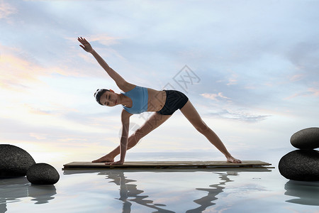 石分三面年轻女人在水面上练习瑜伽背景