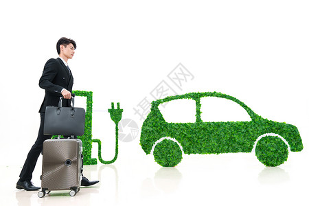充电包青年男士推着行李箱走在电动汽车旁背景