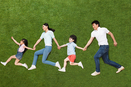 幸福的一家四口手牵手侧卧在草地上图片