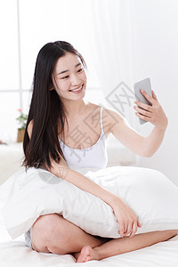 青年女人在卧室使用手机图片