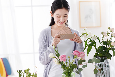 青年女人为鲜花拍照背景