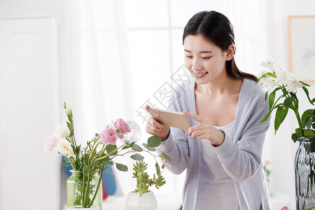 青年女人为鲜花拍照图片