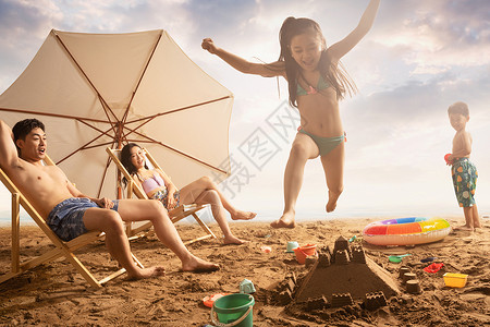 沙滩上年轻父母看着嬉戏的孩子图片