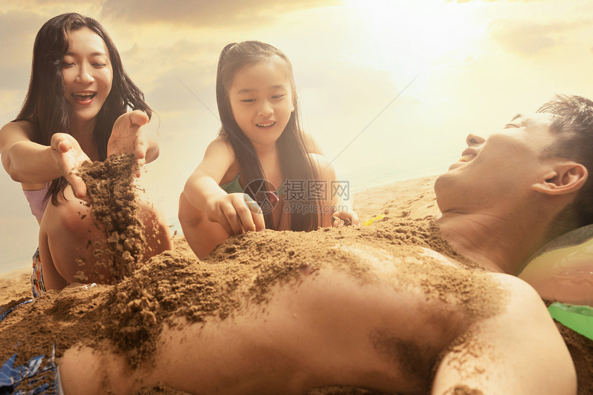 快乐的三口之家在沙滩上玩耍图片