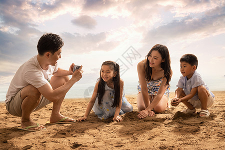 男的夏天沙滩上青年男人为妻子孩子拍照背景