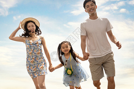 幸福的一家三口在沙滩上散步图片