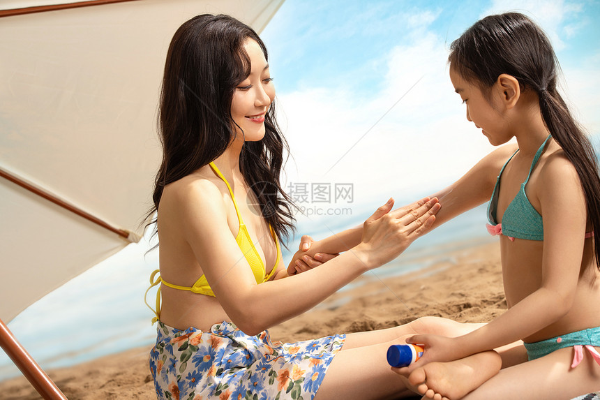 幸福母女在沙滩上擦防晒霜图片