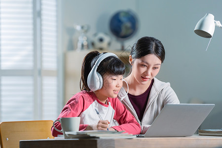 专注电脑年轻妈妈辅导女儿上网课背景
