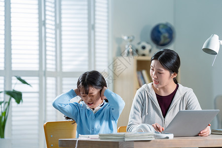 年轻妈妈和做作业的女儿生气高清图片