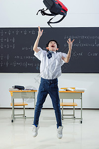 飞起来的书包快乐的小学男生在教室里欢呼跳跃背景