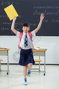 黄色裙子的女生快乐的小学女生在教室里欢呼跳跃背景