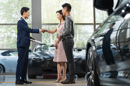 汽车握手服务汽车销售人员和青年夫妇握手背景