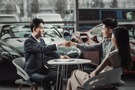 汽车销售人员和青年夫妇握手高清图片