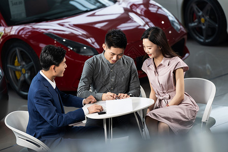 汽车销售人员与青年夫妇确认购车意向背景图片