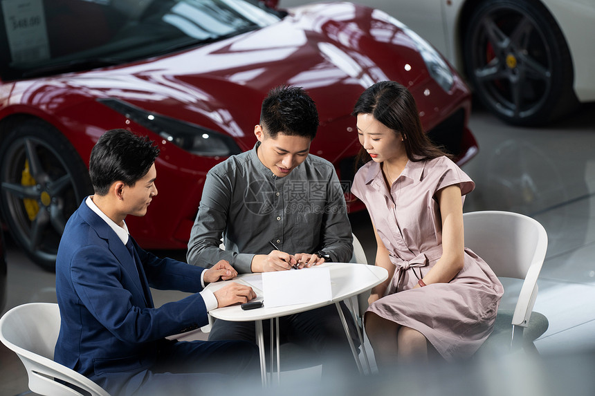 青年夫妇与汽车销售人员签订合同图片