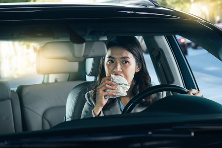 面包工具驾驶汽车的青年女人吃食物背景
