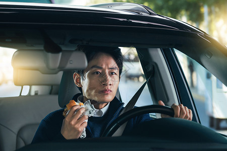 驾驶汽车的青年男人吃食物图片