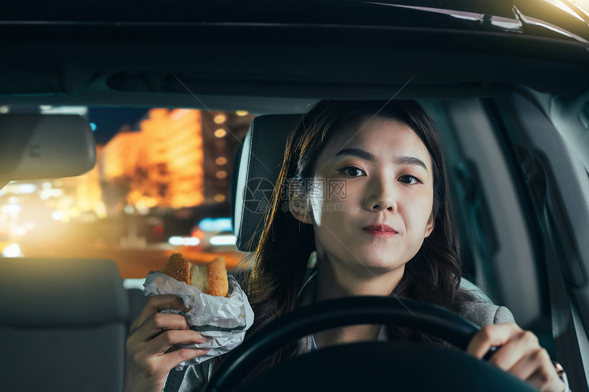 驾驶汽车的青年女人吃食物图片