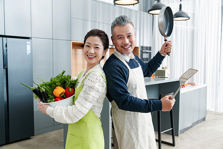 拿着铲子男人快乐的中老夫妇在厨房做饭背景