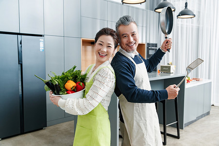 平底锅和铲子快乐的中老夫妇在厨房做饭背景