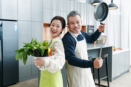 平底锅和铲子快乐的中老夫妇在厨房做饭背景