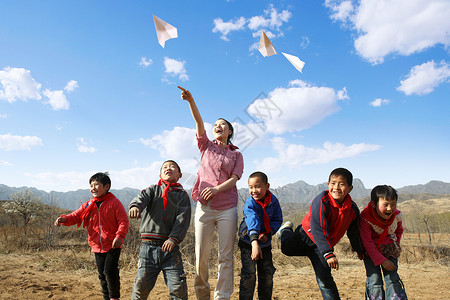 跳跃玩耍男孩乡村老师和学生放纸飞机背景