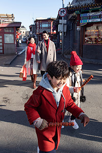 抽冰尜的男孩拿着糖葫芦的小朋友和父母逛街背景