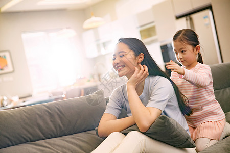 孩子为妈妈梳头发母亲和女孩在客厅背景