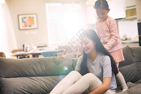 孩子为妈妈梳头发母亲和女孩在客厅背景