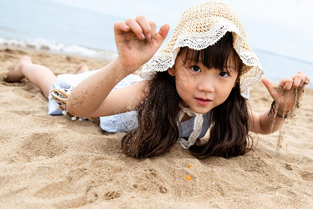 趴在海滩上玩耍的小女孩图片