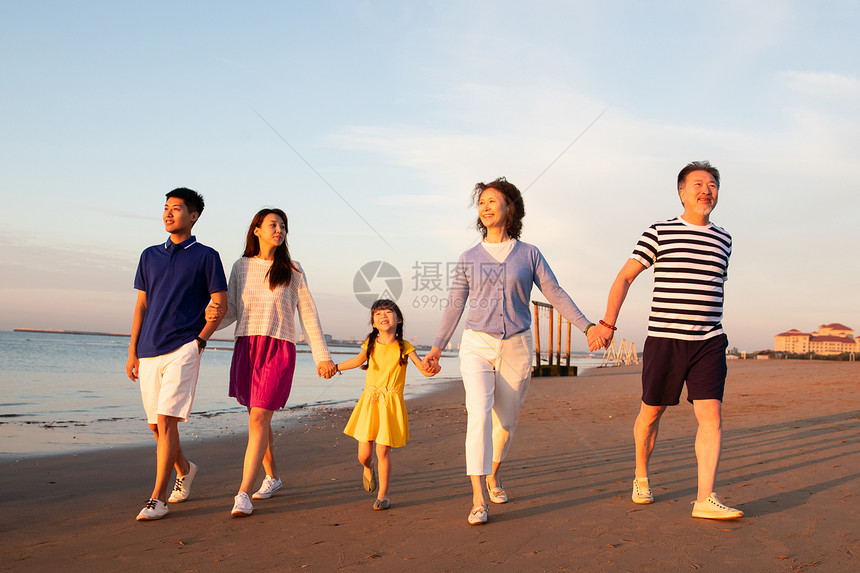 夕阳下在海边散步的幸福家庭图片