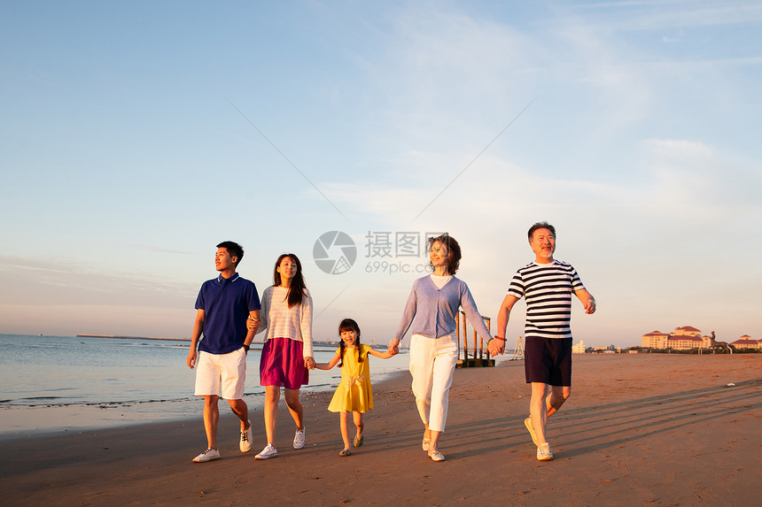 夕阳下在海边散步的幸福家庭图片