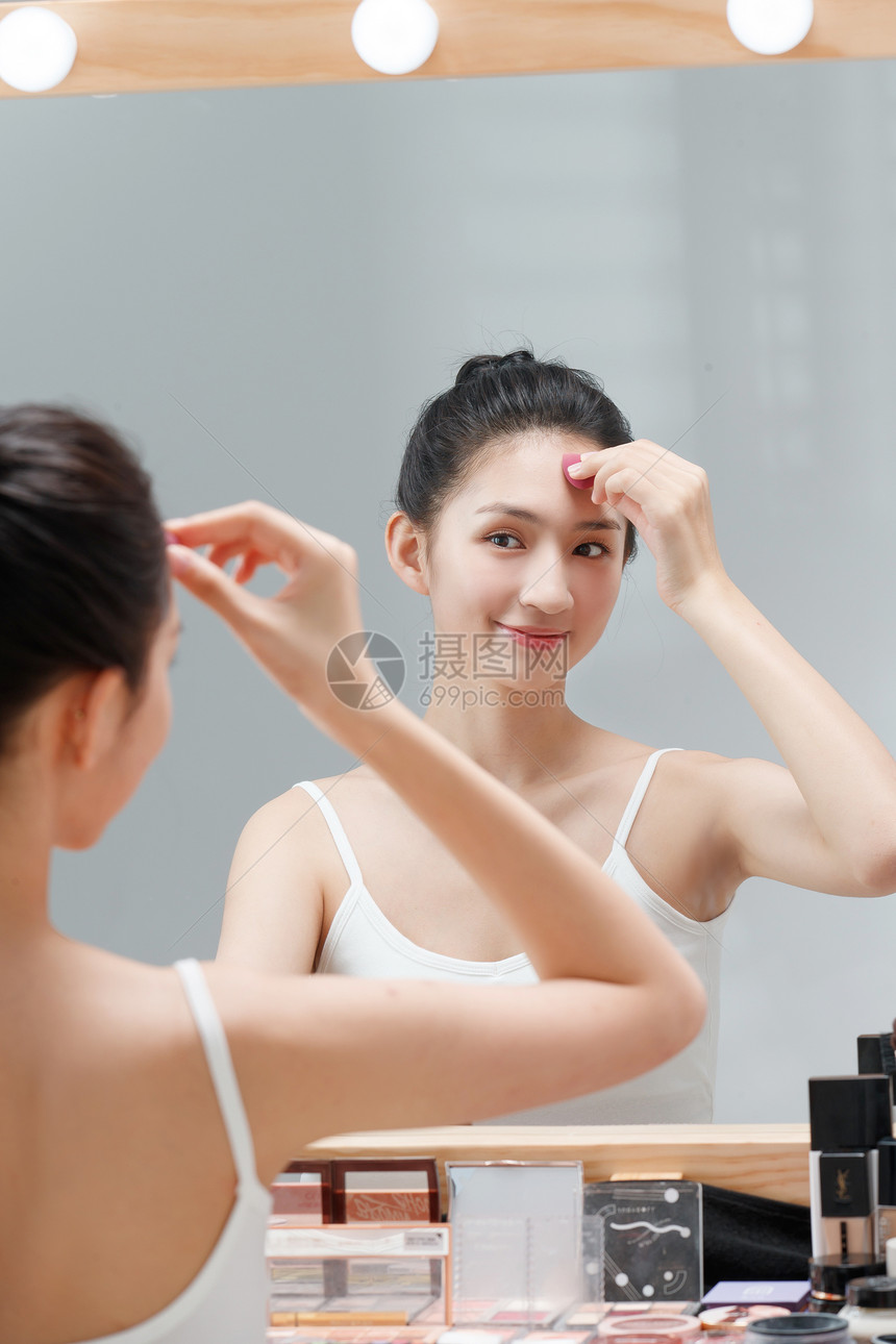年轻女人对着镜子化妆图片