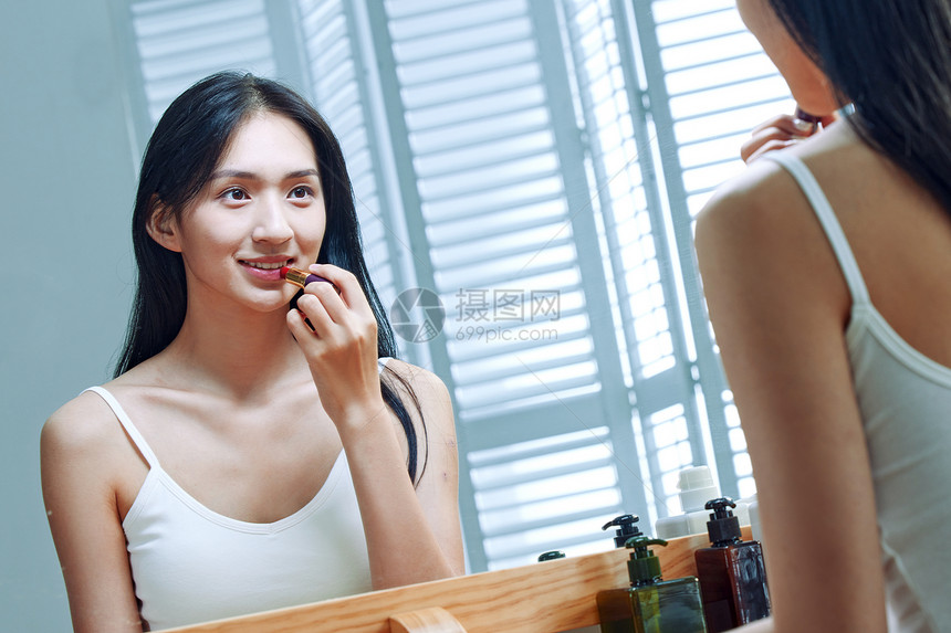 漂亮的年轻女人照着镜子涂口红图片