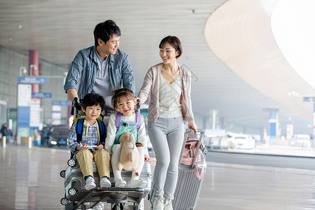 推着行李的女孩快乐家庭推着行李在机场背景