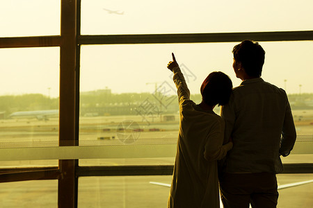伸手背影青年情侣在机场候机厅往外看背景