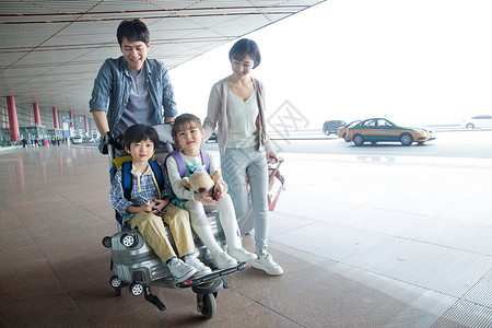 提着行李的男孩欢乐家庭在机场推着行李背景