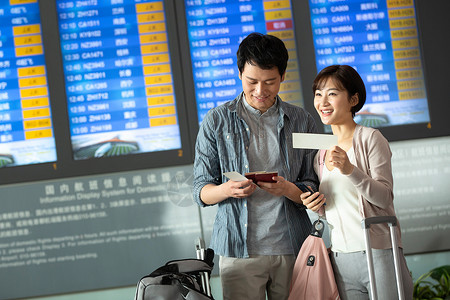 拉杆箱包青年情侣在机场候机厅拿着机票背景