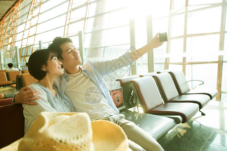 青年情侣坐在机场候机厅看手机图片