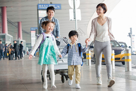 推着花的男孩欢乐家庭在机场推着行李背景