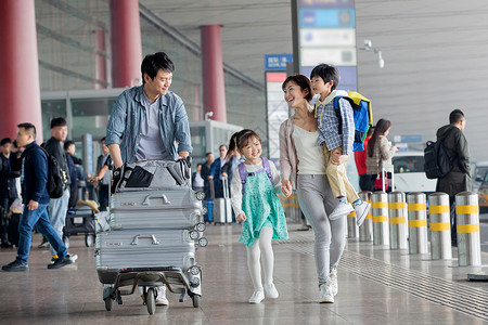推着花的男孩欢乐家庭在机场推着行李背景
