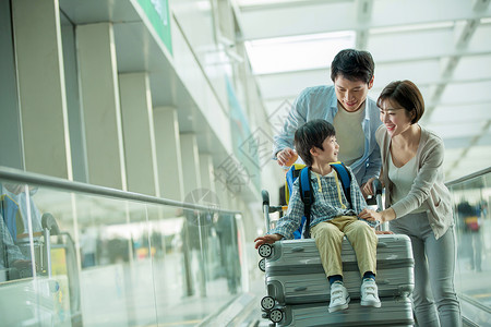 推着花的男孩一家三口在机场推着行李背景