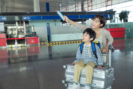 儿童拉杆箱年轻妈妈带着孩子在机场候机大厅背景