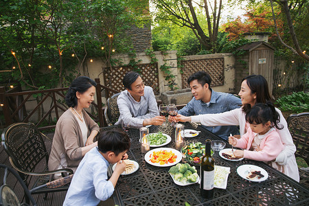 喝红酒女孩快乐大家庭在庭院里用餐背景