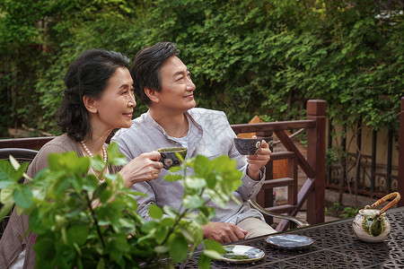 地产活动老年夫妇坐在院子里喝茶背景