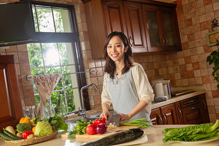 黄瓜鱼青年女人在厨房里做饭背景