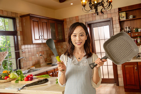 铲子勺子青年女人在厨房里做饭背景