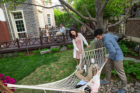 网编吊床快乐家庭在庭院里玩耍背景